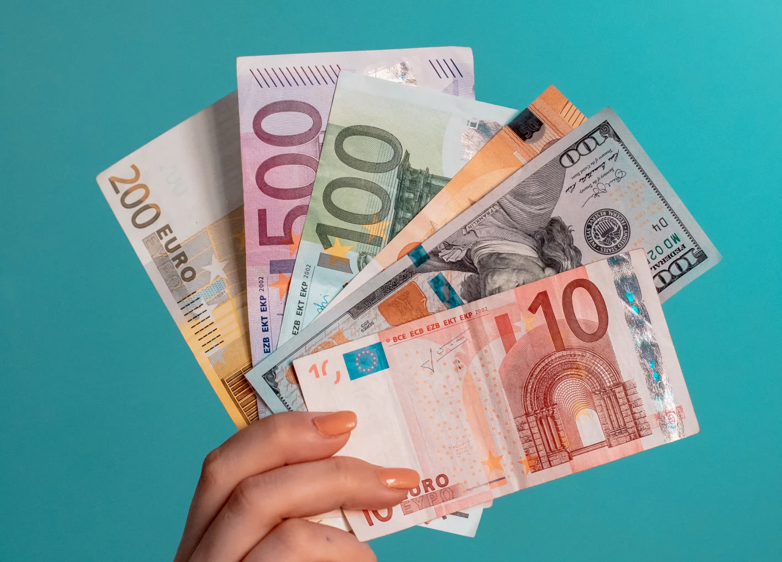 Die Hand einer Frau hält mehrere Euro-Banknoten auf blauem Hintergrund und symbolisiert ein Startup.